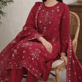 Woman wearing a red embroidered traditional outfit sitting on a chair.