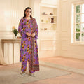 Woman in a purple floral outfit standing in a well-lit room with a bookshelf in the background.