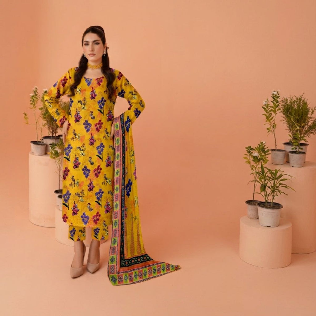 Woman in a yellow floral dress with a colorful scarf standing against a peach background with potted plants.